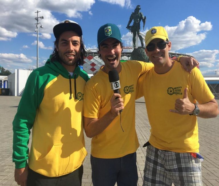 Membros do MVA em frente de estádio na copa da Rússia pousando com microfone da Globo na mão